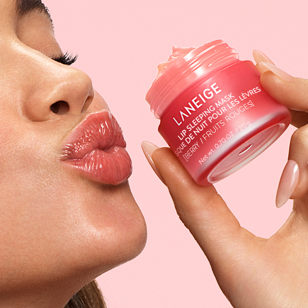 Mujer sonriendo aplica Laneige Lip Sleeping Mask Berry con la espátula, mostrando labios hidratados.