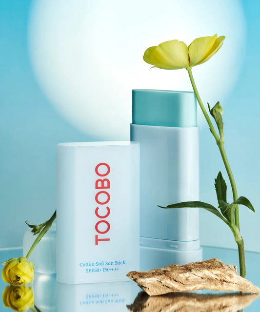 Tocobo Cotton Soft Sun Stick con elementos naturales como flores y plantas, en fondo luminoso.