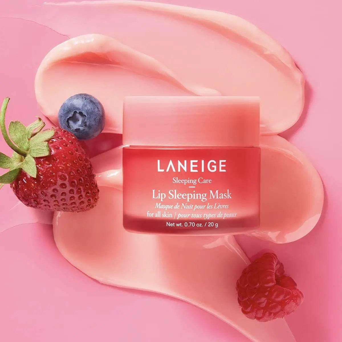Tarro de Laneige Lip Sleeping Mask Berry de 20 g sobre dos brochazos de producto rosa, acompañado de una fresa y un arándano contra fondo rosa.