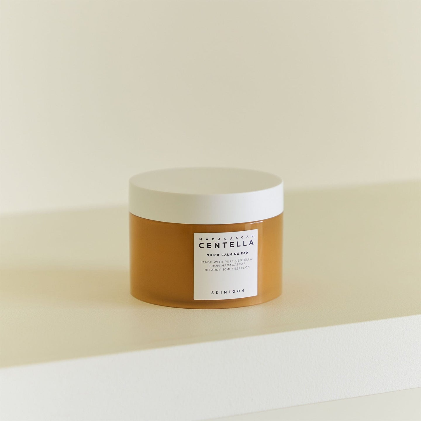 Envase de Skin1004 Madagascar Centella Quick Calming Pad de 70 almohadillas (130 ml) situado sobre una mesa clara, fondo beige.