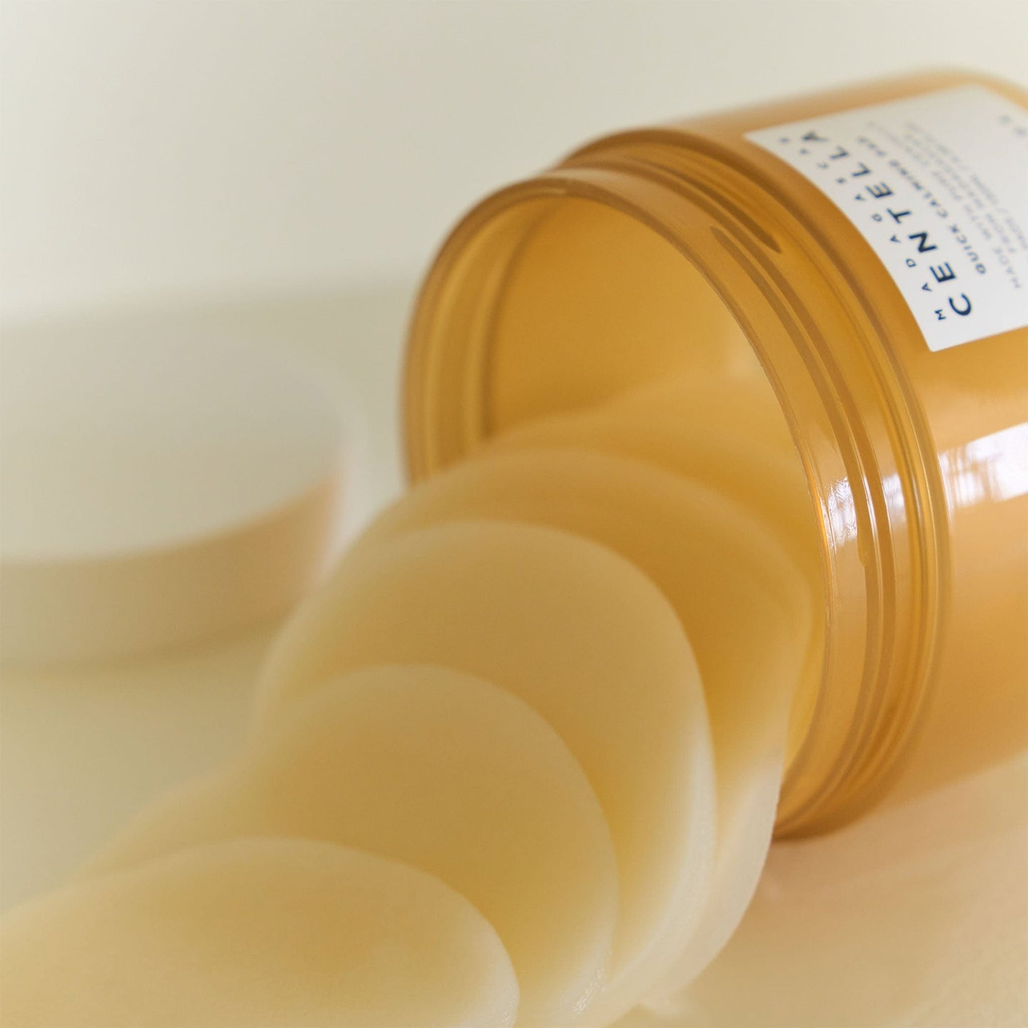 “Primer plano de almohadillas del Skin1004 Madagascar Centella Quick Calming Pad saliendo de un bote inclinado, mostrando su textura suave y empapada