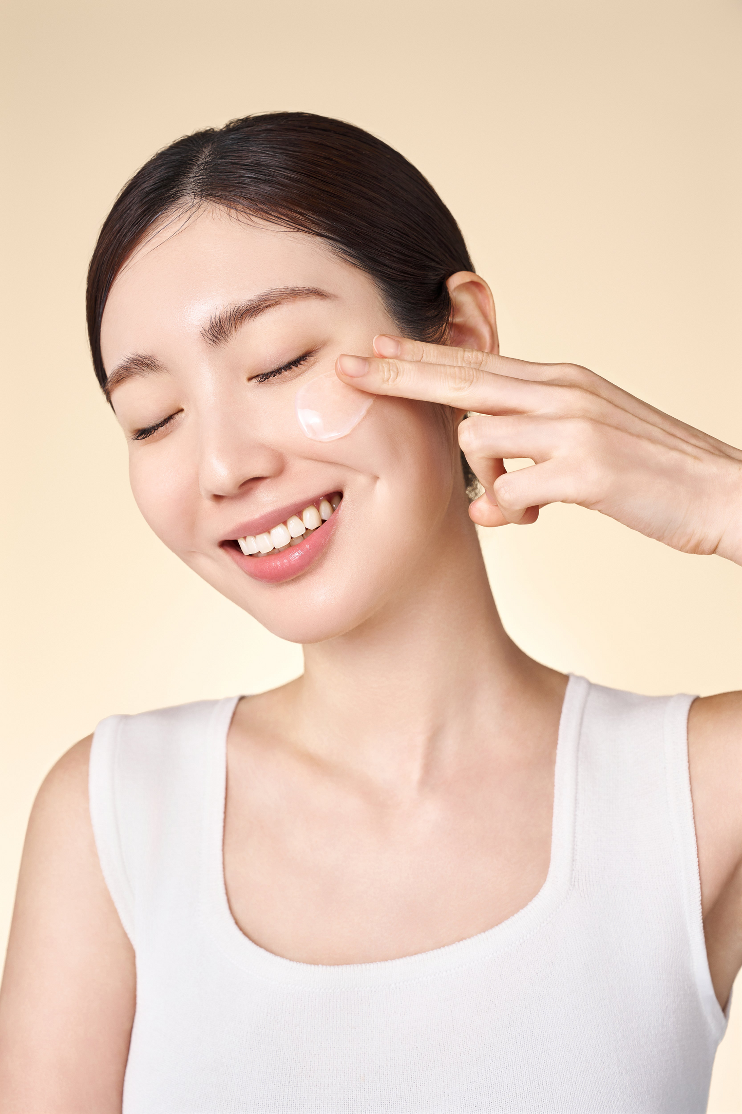 Modelo aplicando Purito Oat-In Calming Gel Cream en su mejilla con los dedos, ojos cerrados y fondo beige suave.