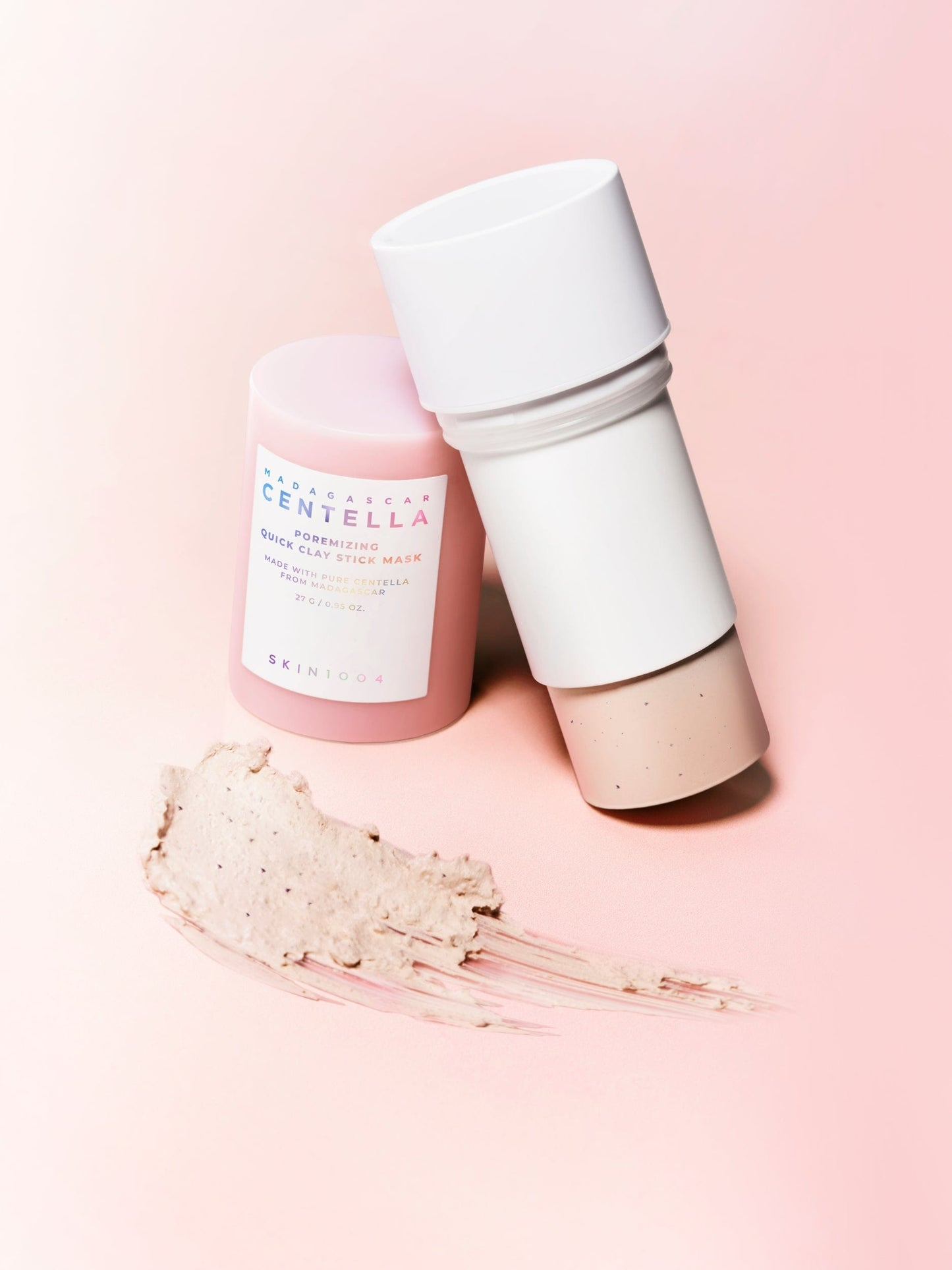 Alt-text:
Stick de mascarilla Skin1004 Madagascar Centella Poremizing Quick Clay Stick Mask con la barra abierta y textura beige extendida, fondo rosa degradado.