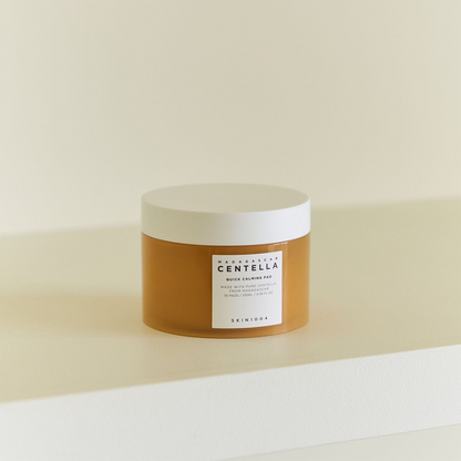 Envase de Skin1004 Madagascar Centella Quick Calming Pad de 70 almohadillas (130 ml) situado sobre una mesa clara, fondo beige.
