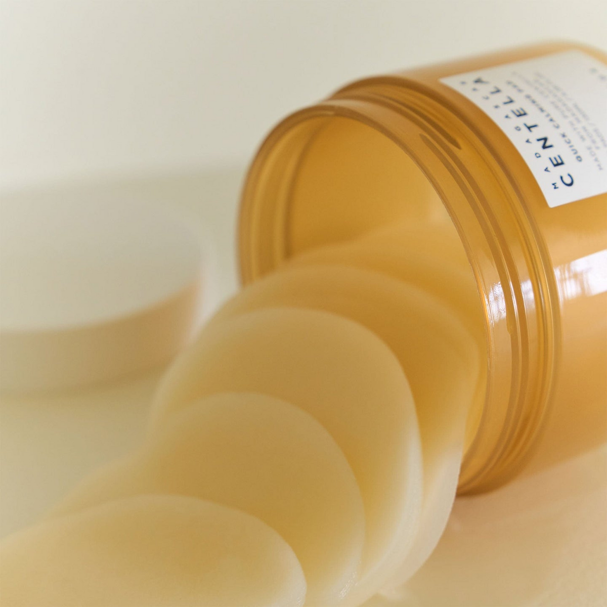 “Primer plano de almohadillas del Skin1004 Madagascar Centella Quick Calming Pad saliendo de un bote inclinado, mostrando su textura suave y empapada